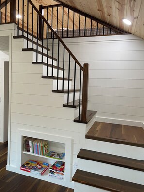 A staircase with wooden steps and black railings, leading to a loft area with a sloped ceiling.