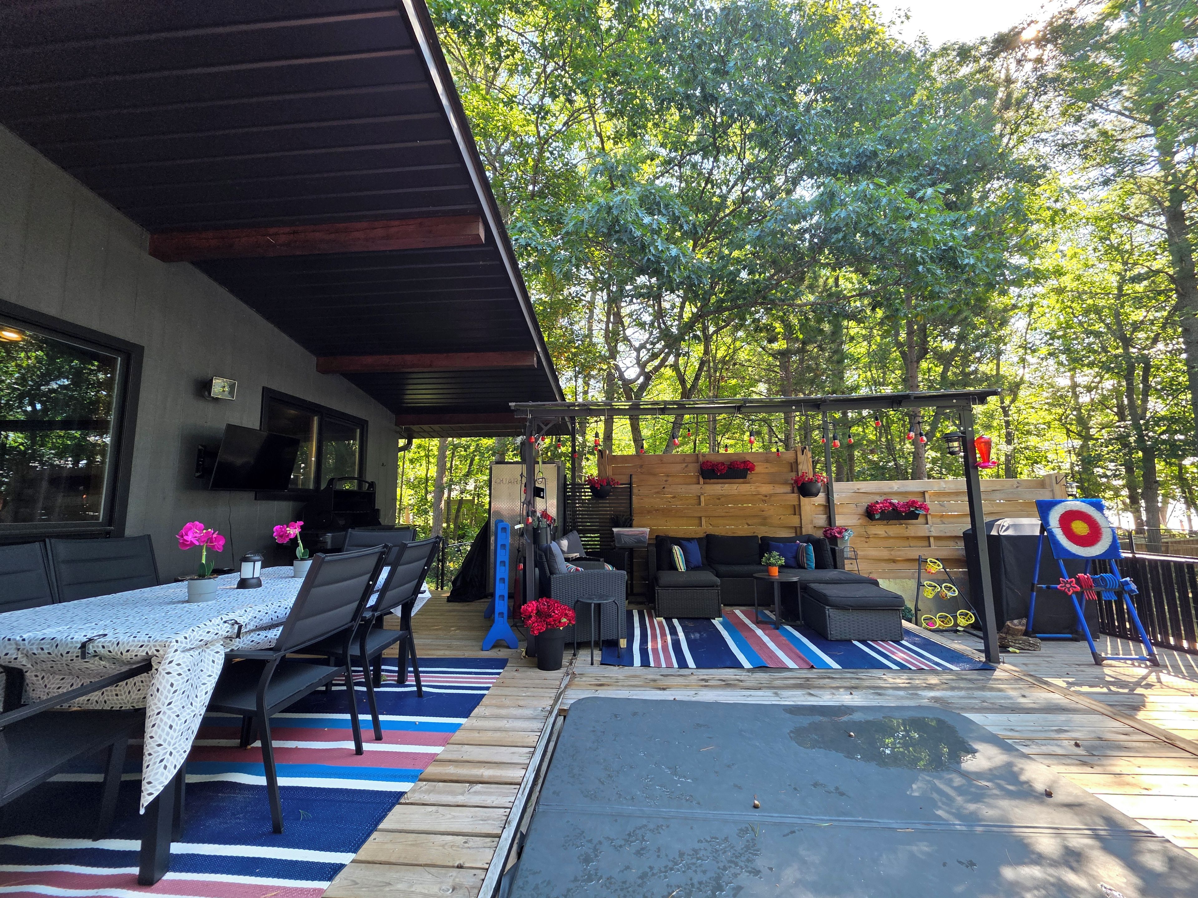 An outdoor patio with a dining area, seating, and a target game.