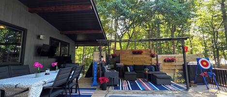 An outdoor patio with a dining area, seating, and a target game.