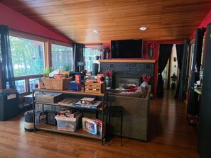 A cozy living room with a fireplace, wooden flooring, and a television mounted above it.