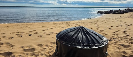 A beach with a black object on the sand, a clear sky, and the ocean in the background.