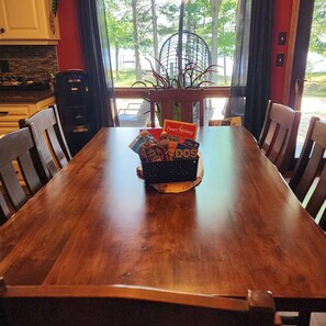 A wooden dining table with a black basket containing food items and a card.