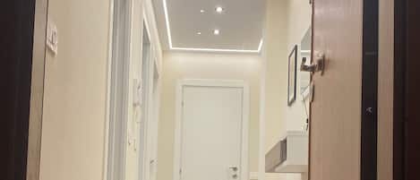 A hotel hallway with a welcome mat, doors, and recessed lighting.