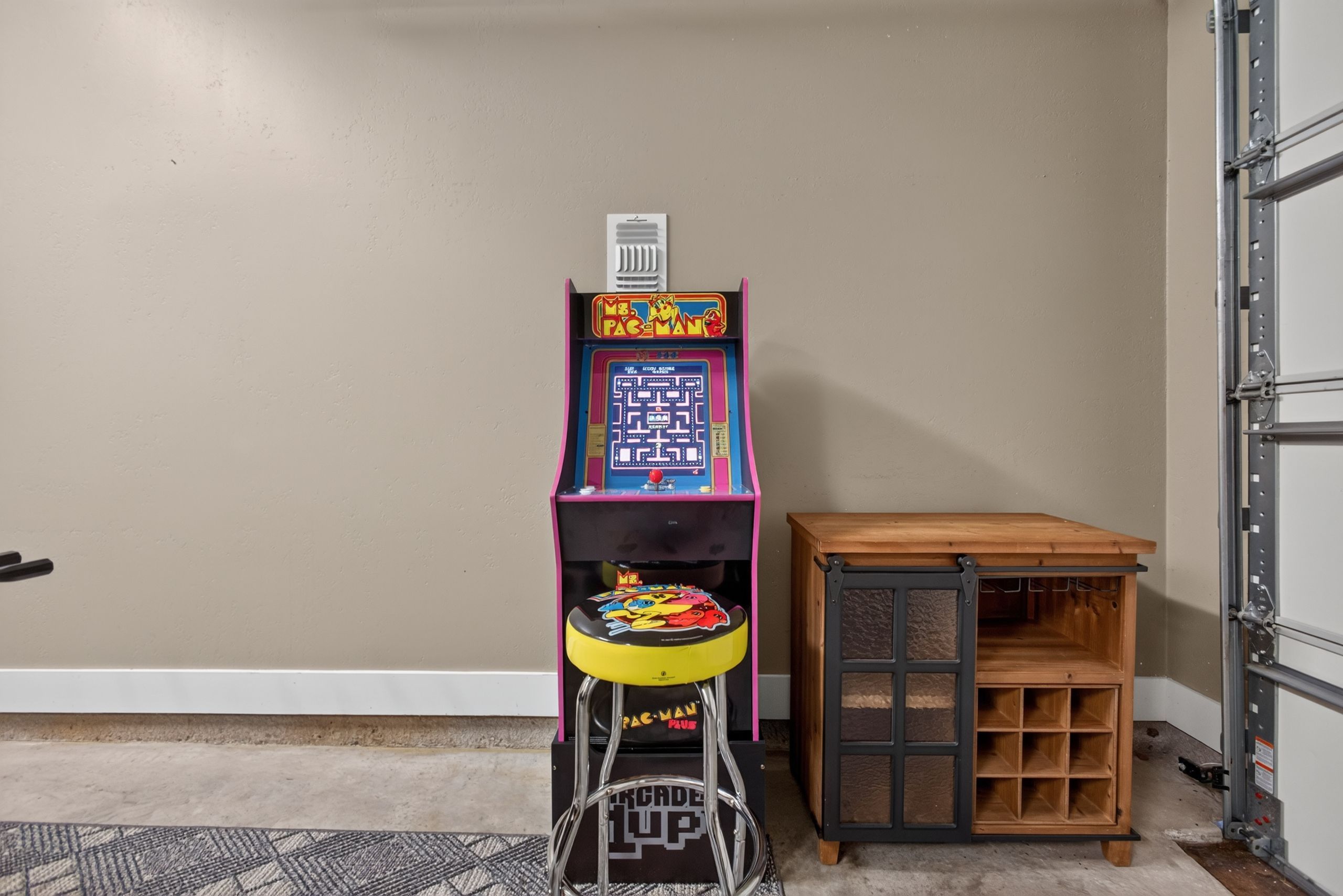 A room with a vintage arcade machine, a small wooden table, and a metal cabinet.