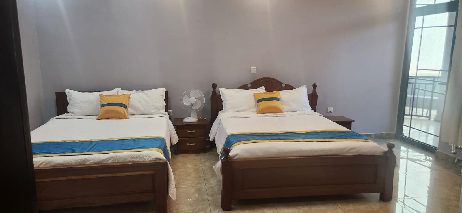 Habitación de hotel con dos camas, una mesita de noche, un ventilador y una ventana.