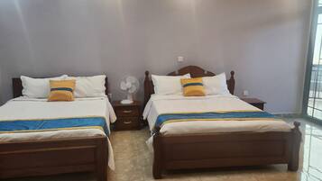 Habitación de hotel con dos camas, una mesita de noche, un ventilador y una ventana.