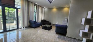 Ein modernes Wohnzimmer mit einer großen Schiebeglaswand, einem Sofa, einem Couchtisch und einem dekorativen Regal.