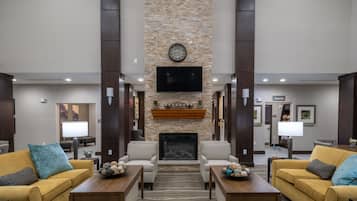 A lobby with a stone fireplace, two sofas, a television, and a sign for the pantry.