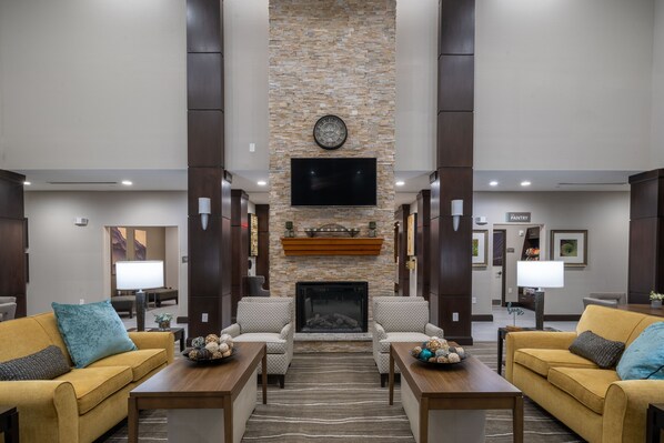 A lobby with a stone fireplace, two sofas, a television, and a sign for the pantry.