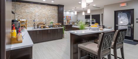 A modern kitchen with a stone backsplash, a buffet counter, and a seating area with bar stools.