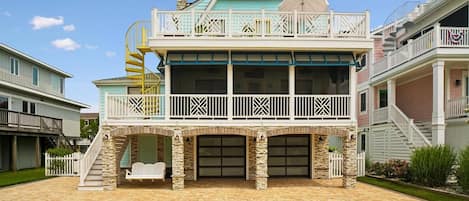 A two-story house with a balcony, a garage, and a stone foundation.