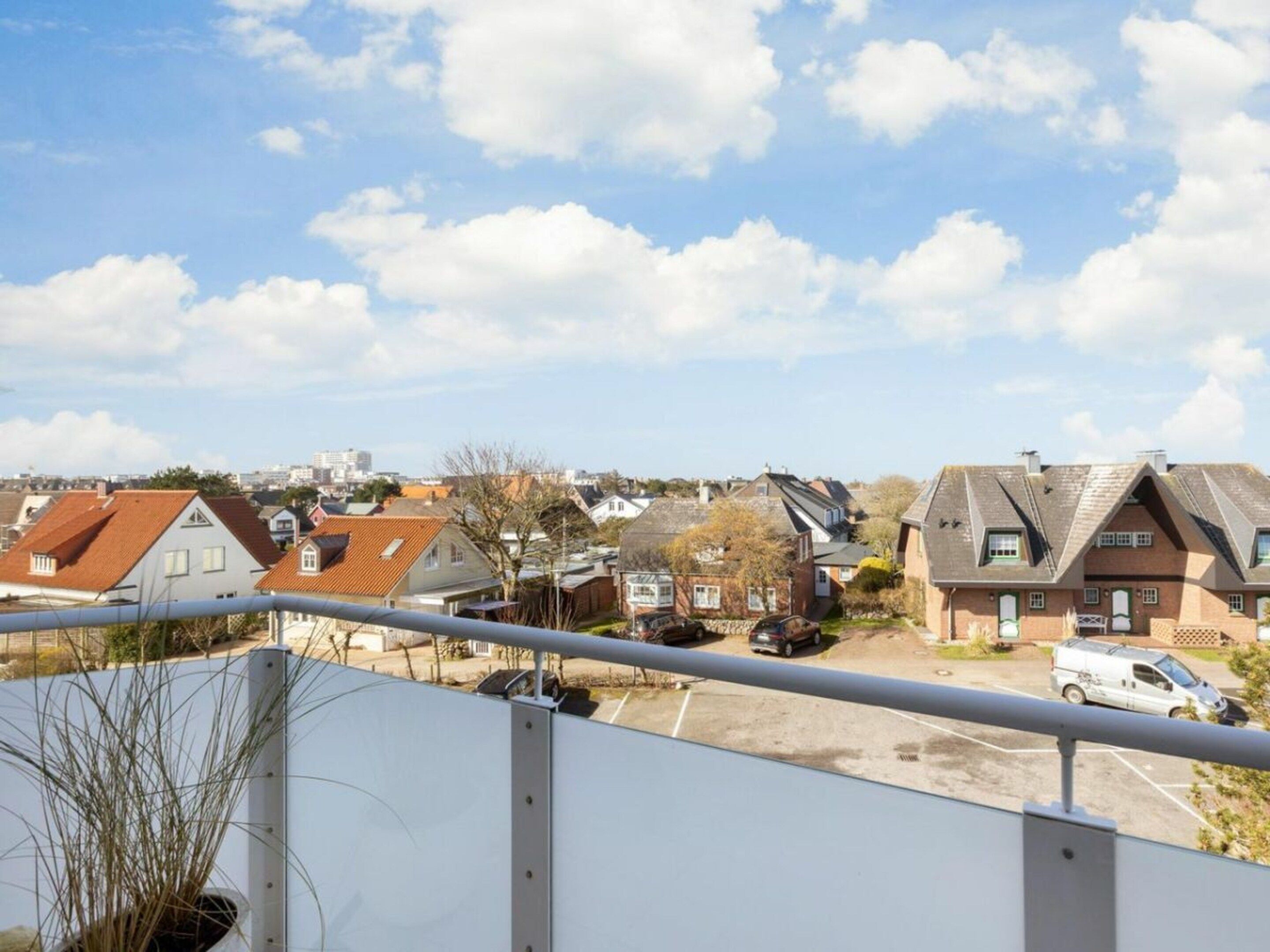 A residential area with houses, a parking lot, and a clear sky.