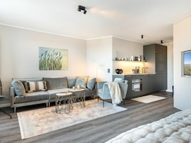 Una sala de estar moderna con un sofá gris, una mesita redonda y un cuadro en la pared.