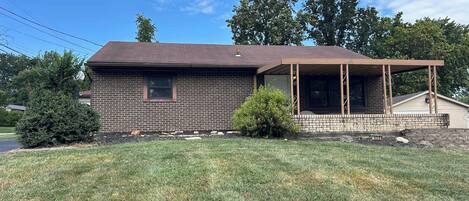 A single-story brick house with a porch and a small front yard.