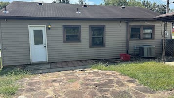 A single-story house with a front door, two windows, and an air conditioning unit.