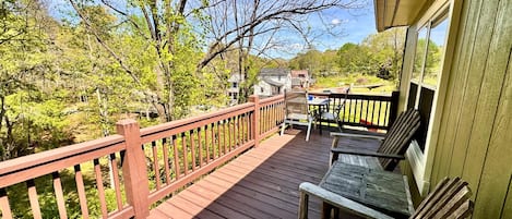 A wooden deck with a railing, a table, and two chairs.
