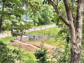 A stone patio with outdoor seating, surrounded by trees and a grassy area.