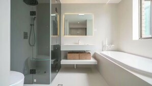 Une salle de bain moderne avec une douche à parois de verre, un lavabo blanc et un grand miroir.