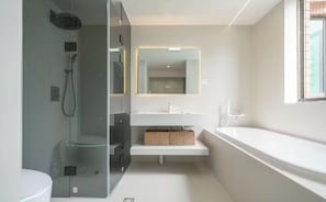 Un baño moderno con cabina de ducha de vidrio, un lavamanos blanco y un espejo grande.