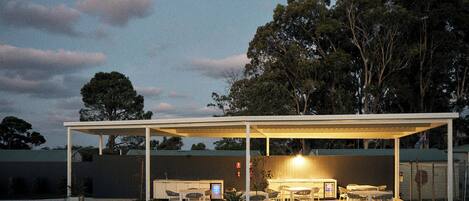 A covered outdoor patio area with seating and a built-in kitchen.