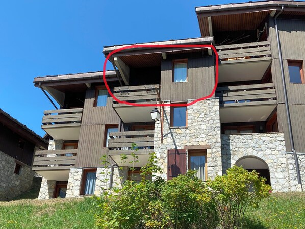 Un edificio de varios pisos con balcones, fachada de piedra y cielo despejado.
