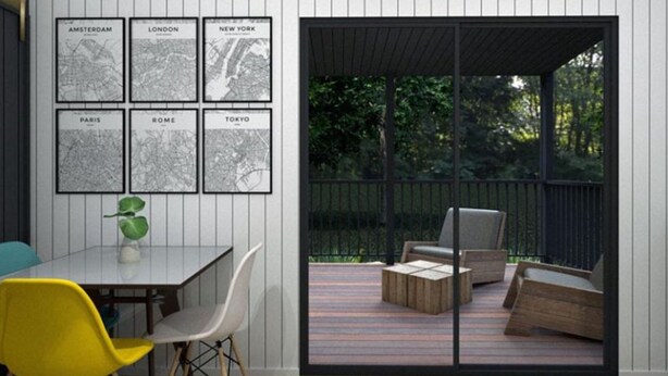 Un interior moderno con comedor, una puerta de vidrio que da a una terraza exterior y mapas de la ciudad enmarcados en la pared.