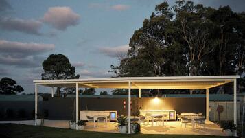 A covered outdoor patio area with seating and a built-in kitchen.