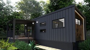 Eine moderne, dunkel gestaltete Hütte mit überdachter Veranda, einer kleinen Terrasse und einem gepflasterten Zugangsbereich.