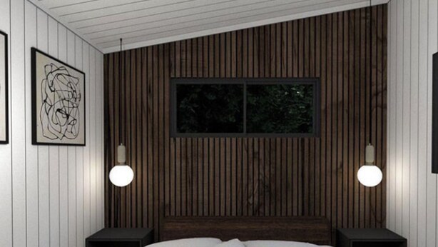 Een slaapkamer met een wand van houten latten, een bed met wit bedlinnen, twee nachtkastjes en twee wandlampen.