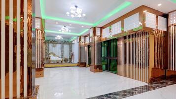 Un hall d’hôtel spacieux, doté d’un sol en marbre, d’une scène avec un canapé blanc et de panneaux décoratifs.
