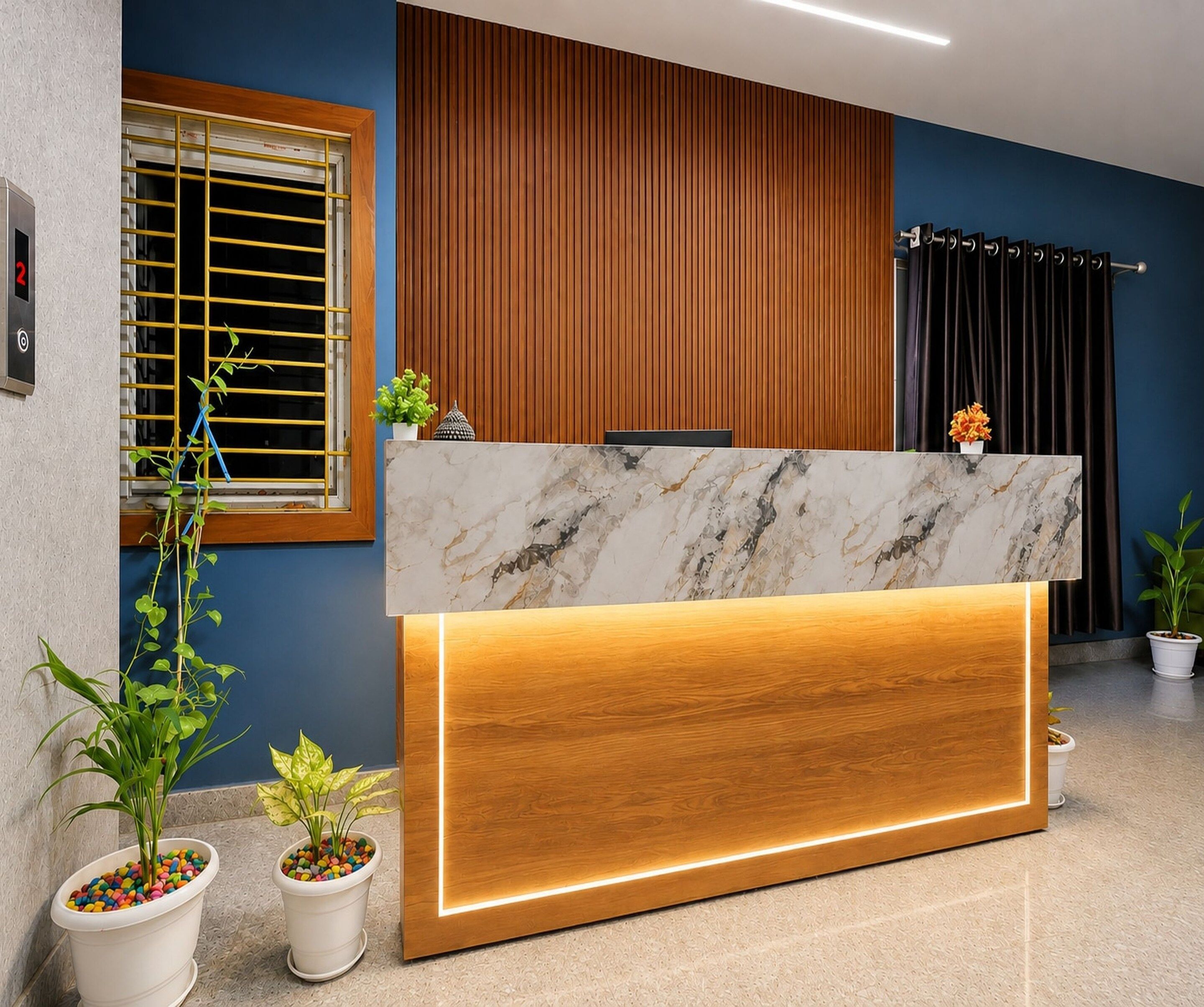 A reception desk with a marble top and wooden base, flanked by potted plants and a window with yellow blinds.