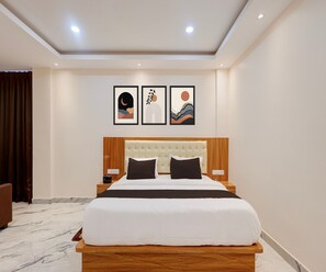 A hotel room with a large bed, a wooden headboard, a marble floor, and three framed artworks on the wall. - Classic Kamala Resort (Bhubaneshwar)