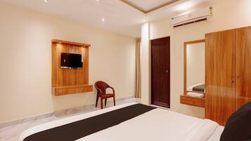 Une chambre d’hôtel avec un lit, une armoire en bois, un téléviseur fixé au mur et une chaise.