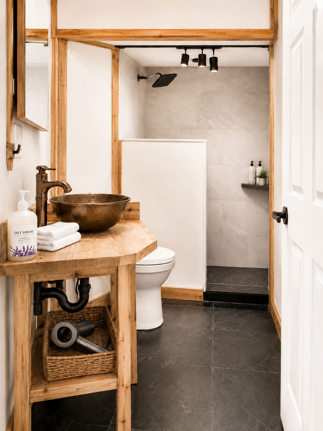 A bathroom with a wooden vanity, a large basin, a toilet, and a shower.