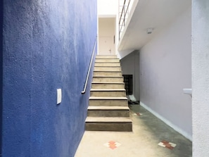 Una escalera que conduce a un piso superior, con una pared azul a un lado y una pared blanca al otro.