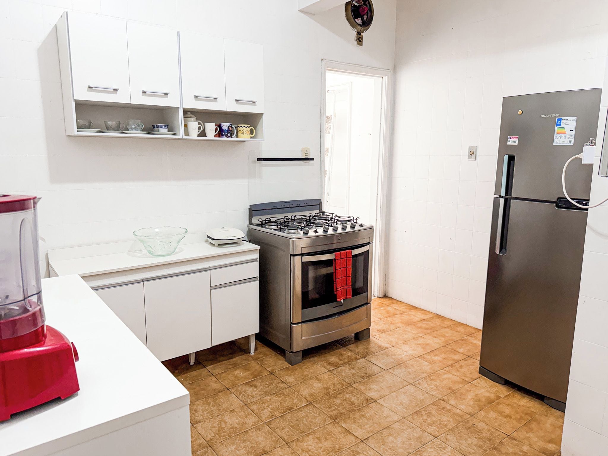 Une cuisine avec des meubles blancs, une cuisinière à gaz, un four en acier inoxydable et un réfrigérateur.