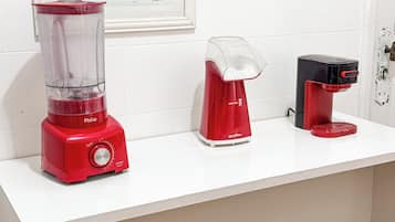 Una encimera de cocina con una licuadora roja, un hervidor eléctrico blanco y una cafetera negra.