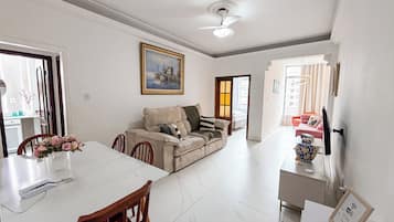 Una sala de estar con un sofá, una mesa de comedor con sillas, un ventilador de techo y un cuadro en la pared.