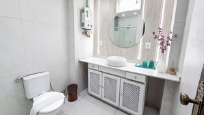 Un baño moderno con inodoro, lavabo, espejo y una planta decorativa.