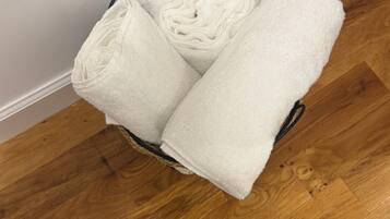 A basket with folded white towels on a wooden floor.