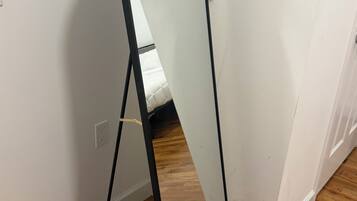 Una habitación con pared blanca, suelo de madera y un soporte de metal negro con un panel blanco.