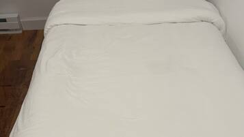 Una cama individual con cabecera de madera y ropa de cama blanca.