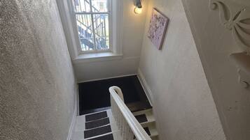 A staircase with white railings and black steps, leading to an exit door with a light fixture above it.