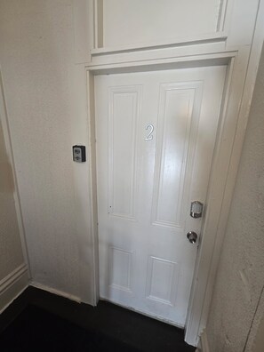 A white door with a number '2' on it, a doorbell, and a door handle. - Budget 2BR Crash Pad  - East Carson St and Parking (Pittsburgh)