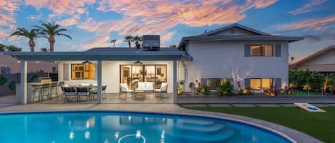 A residential property with a swimming pool, outdoor seating area, and a well-maintained garden.