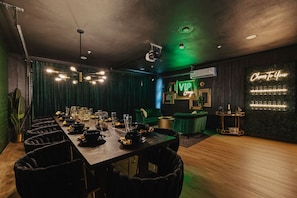 A dining area with a long table set for a meal, a bar area with a neon sign, and a VIP lounge sign. - NEW| POSH Scottsdale |Speakeasy, Pool & Hot Tub (Scottsdale)