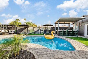 A swimming pool with a swan float, outdoor seating, and a mural with the text 'GOOD TIMES'. - NEW| POSH Scottsdale |Speakeasy, Pool & Hot Tub (Scottsdale)