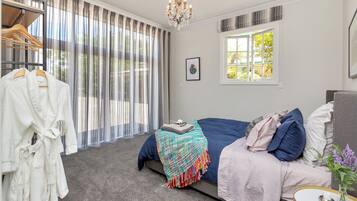 A bedroom with a bed, a bedside table, a window, and a chandelier.