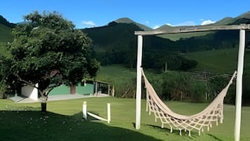 A hammock in a grassy area with a view of a mountain and a building in the background.