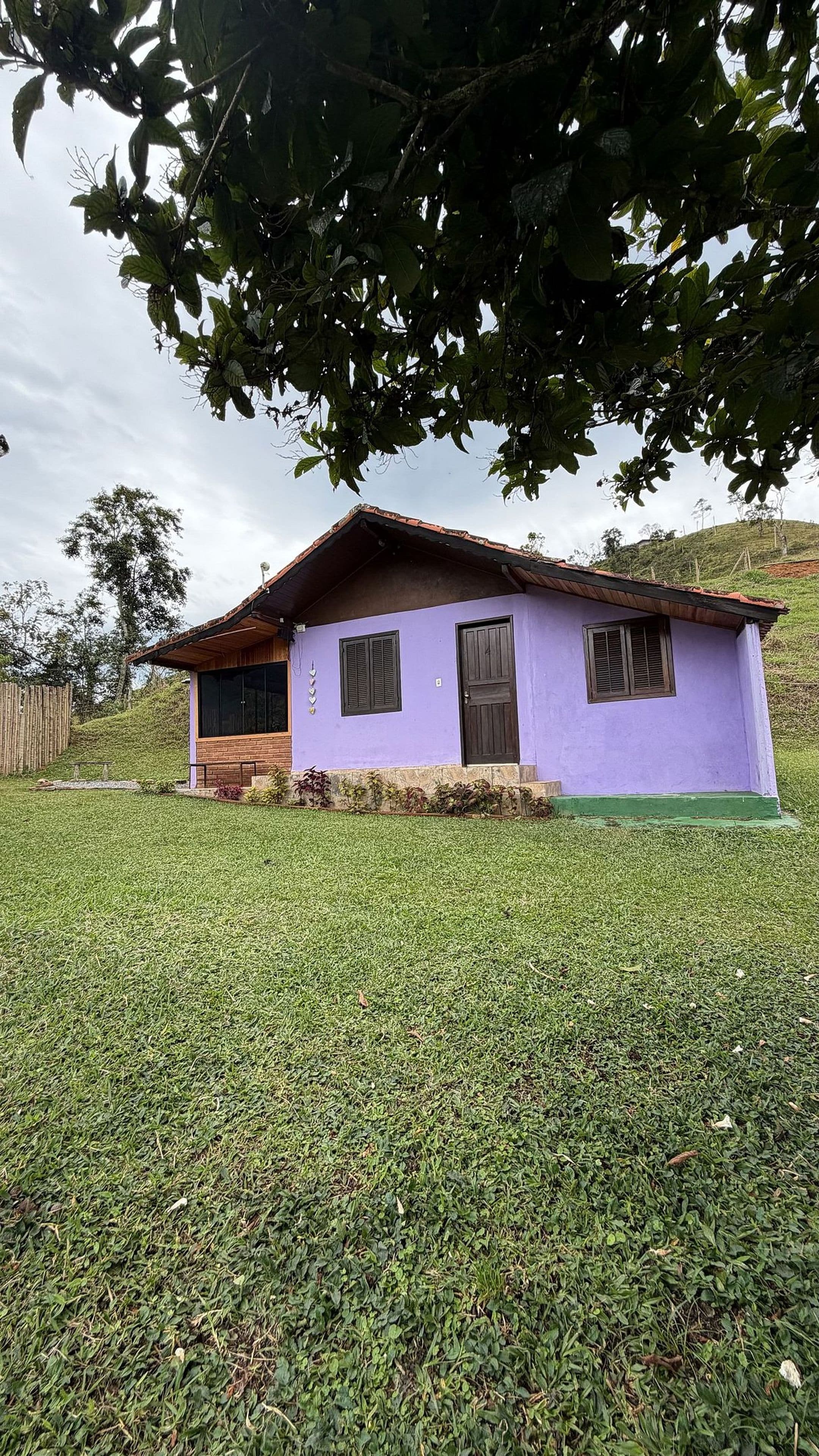 A small house with a sloped roof, a wooden porch, and a purple exterior.